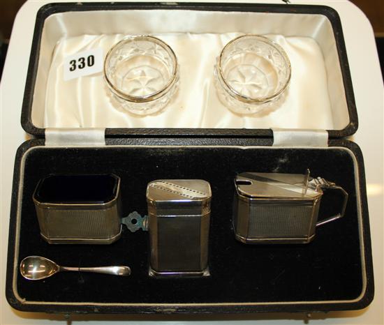 An Art Deco cased silver cruet set and silver rimmed glass salts